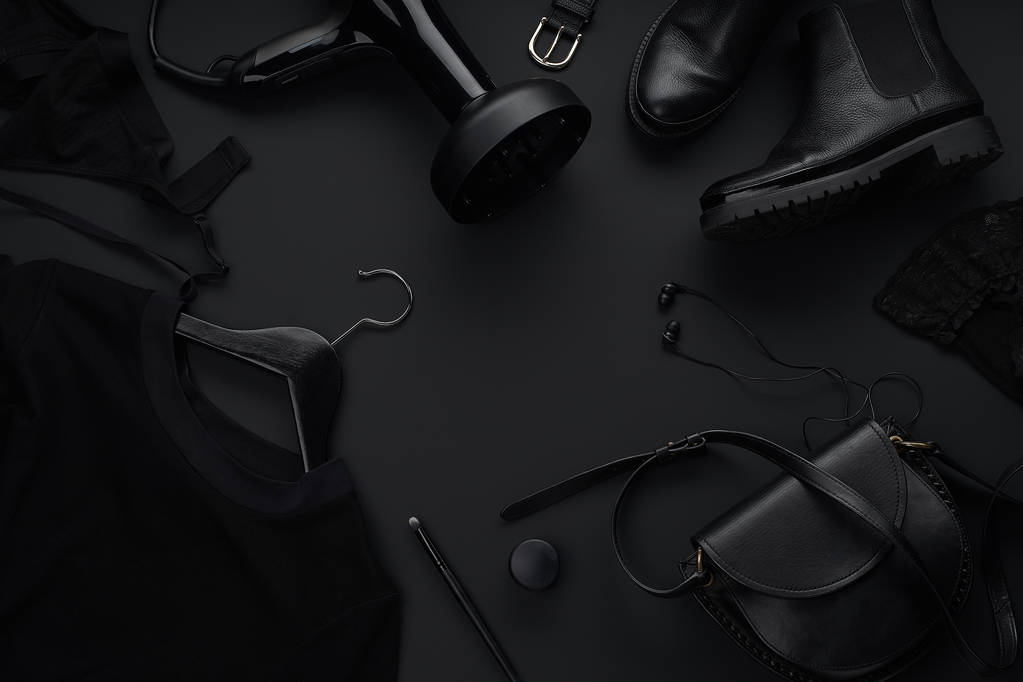 Zwarte monochromatische kleding en accessoires met beauty apparatuur op donkere achtergrond. Black Friday sale concept  - Foto, afbeelding