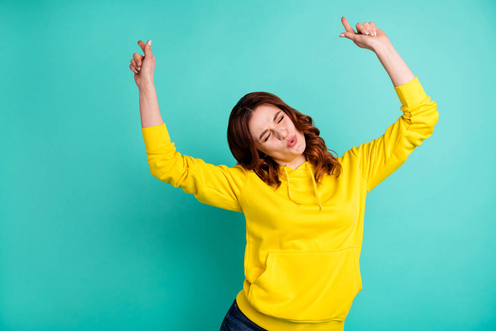 Photo of trendy stylish cheerful cute nice charming clubbing teen inspired dancing with eyes closed in yellow sweater isolated over teal color vivid background - Photo, Image