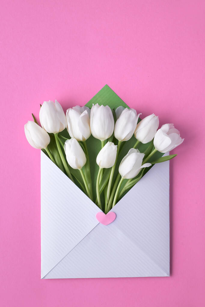Fehér tulipán fehér és zöld borítékban rózsaszín papír háttér - Fotó, kép
