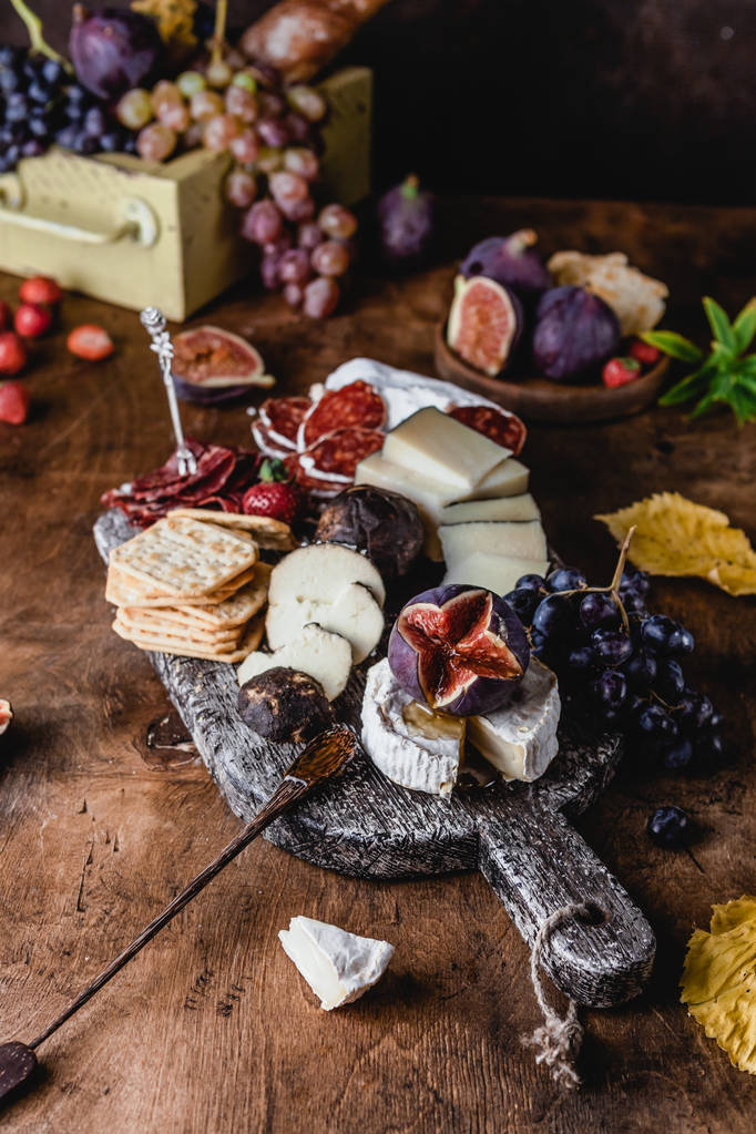 ποικιλία τυριών με σύκα και σταφύλια με ζαμπόν και κράκερ σε μπαγιάτικο φόντο, top view - Φωτογραφία, εικόνα