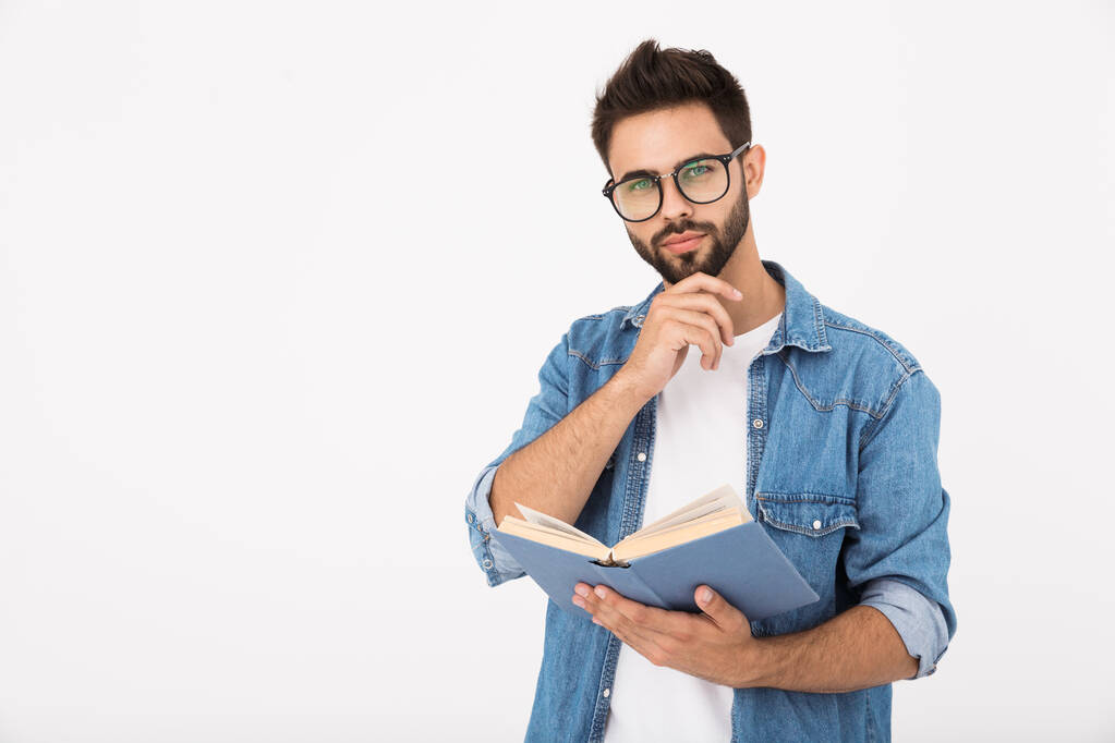 Obrázek seriózního chytrého muže s brýlemi, který drží knihu a dívá se do kamery - Fotografie, Obrázek