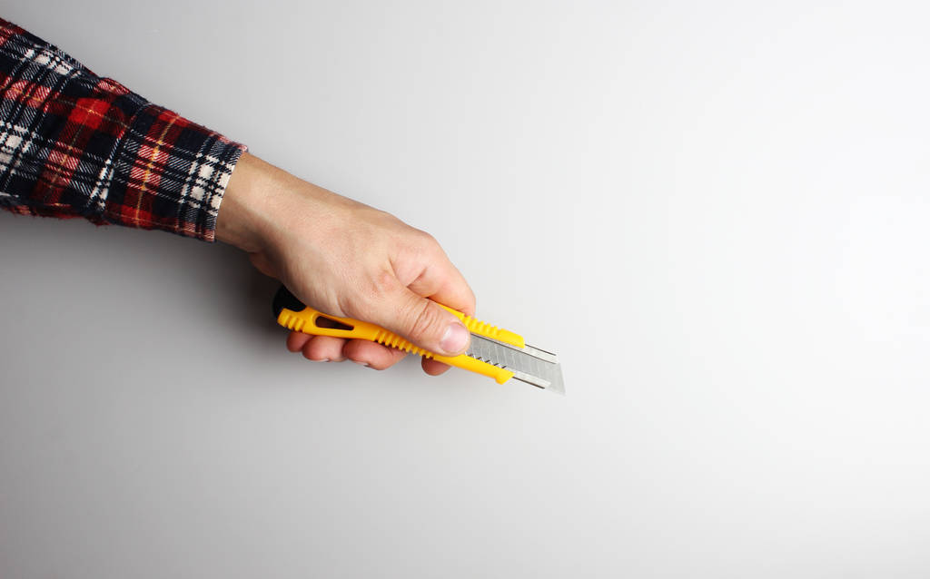 office knife in hand on a gray background - Photo, Image
