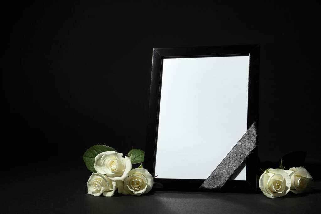 Cadre photo funéraire avec ruban et roses blanches sur table noire sur fond noir. Espace pour le design
 - Photo, image