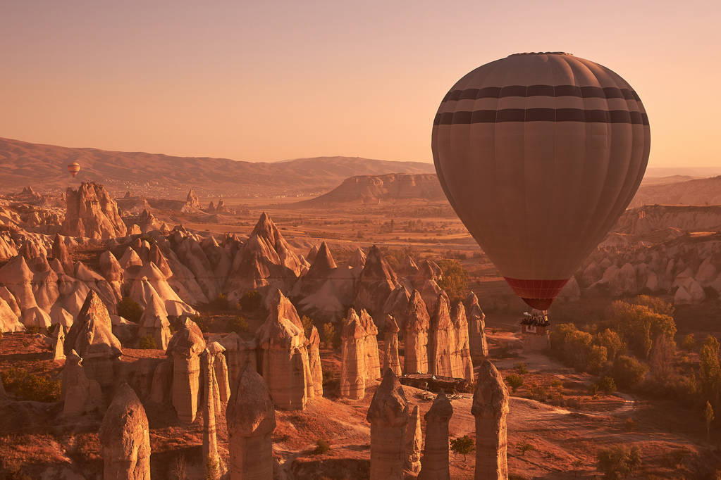 witte grote luchtballon stijgt op in de lucht boven rotsen in Cappadocië - Foto, afbeelding