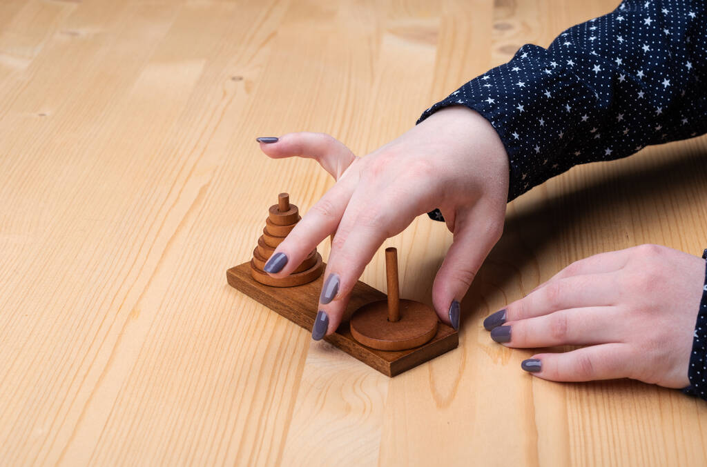 Dziewczyna gra wieża puzzle Hanoi. Ciemny manicure. - Zdjęcie, obraz