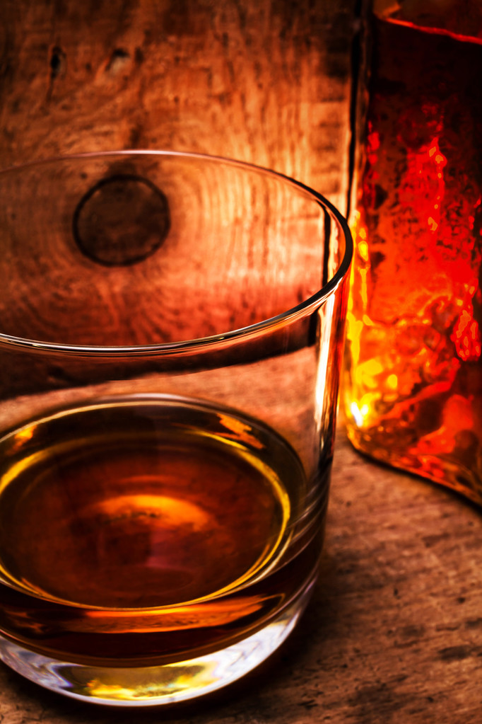 Виски в стакане и бутылка на старом деревянном столе
 - Фото, изображение
