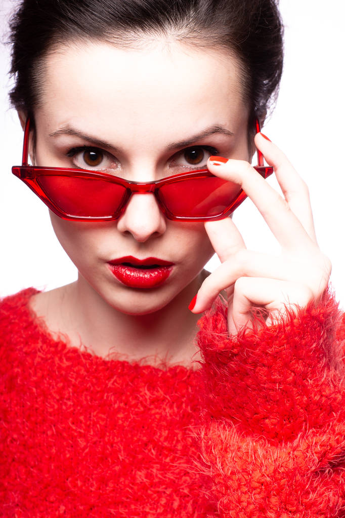 fiatal nő piros napszemüvegben, piros rúzs, piros pulóver - Fotó, kép