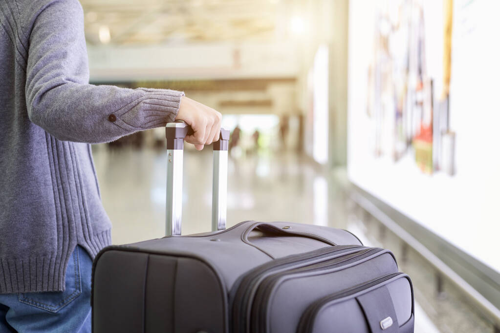 Νεαρός τουρίστας με τα πόδια και τραβήξτε αποσκευές στο αεροδρόμιο - Φωτογραφία, εικόνα