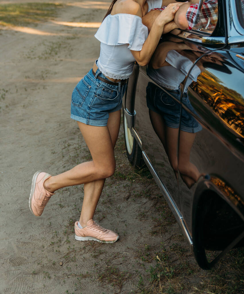 la fille s'approcha de la voiture dans laquelle l'homme est assis, et s'appuya sur la porte de la voiture, flirtant
 - Photo, image