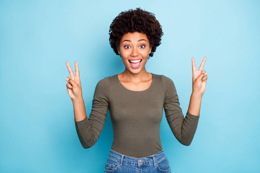 wow hallo Freunde. Porträt von erstaunt afroamerikanischen Mädchen treffen ihre Gefährten genießen Gefühl offen machen V-Zeichen tragen Jugend Stil Pullover Jeans isoliert über blauem Hintergrund - Foto, Bild