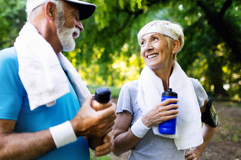Mature or senior couple doing sport outdoors, running in a park - Photo, Image