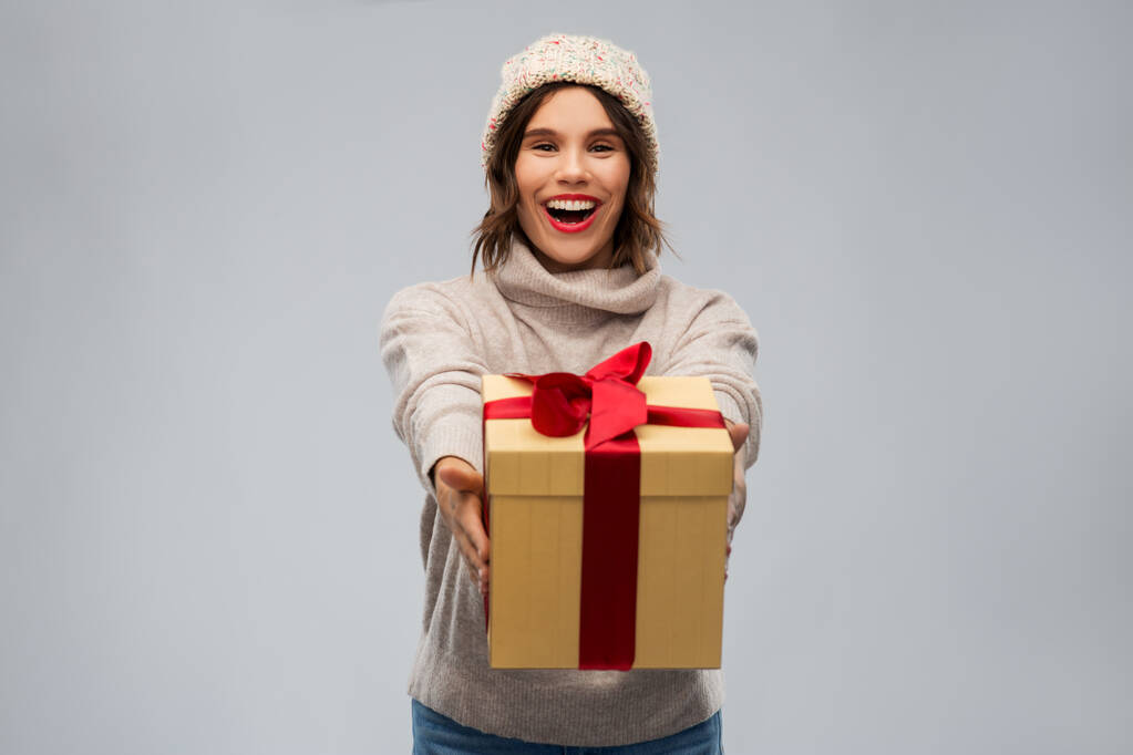 young woman in knitted winter hat holding gift box - Photo, Image