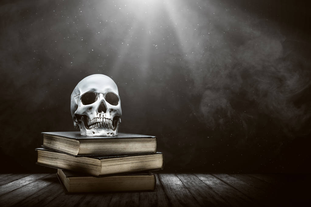 Stapel van het boek met een menselijke schedel op een houten tafel - Foto, afbeelding