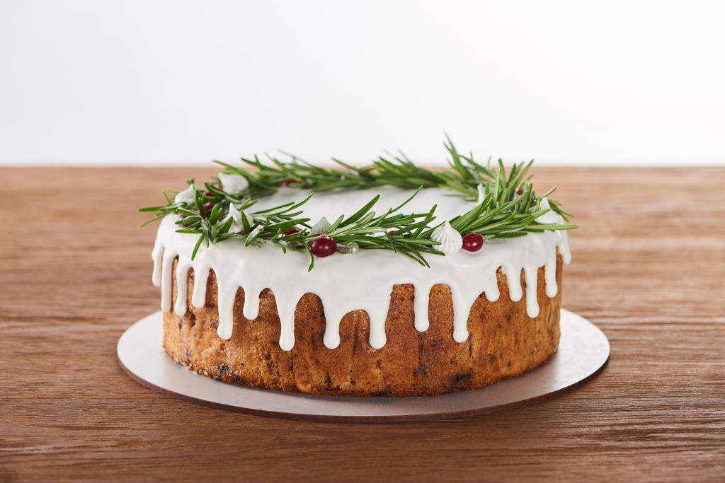 смачний різдвяний торт з білим глазур'ю, розмарином і журавлиною на тарілці на дерев'яному столі
  - Фото, зображення