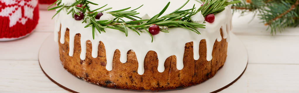 christmas pie with white icing, rosemary and cranberries on white wooden table with spruce branches - Fotografie, Obrázek