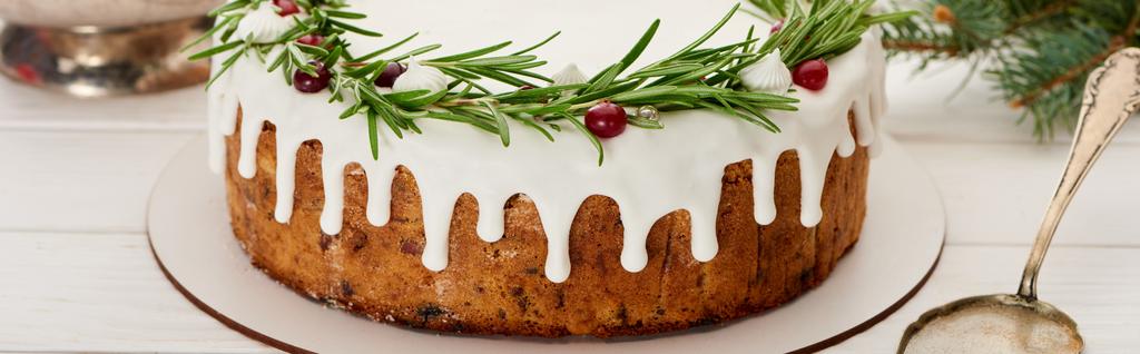 kersttaart met witte glazuur, rozemarijn en veenbessen op witte houten tafel  - Foto, afbeelding