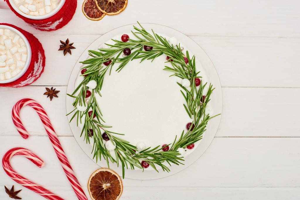 top view of candy canes, two cups of cocoa and christmas pie with icing on white wooden table  - 写真・画像