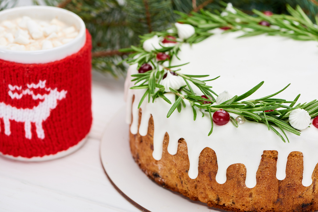 kersttaart met rozemarijn en veenbessen op witte houten tafel met en kopje cacao  - Foto, afbeelding