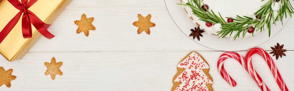 Ansicht von Weihnachtskuchen, Plätzchen und Geschenkschachtel auf weißem Holztisch - Foto, Bild