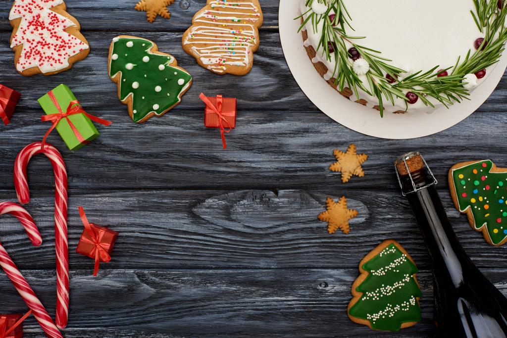 ylhäältä näkymä joulupiirakka, samppanjapullo, karkkia kepit, vähän lahjoja ja evästeitä tumma puinen pöytä
  - Valokuva, kuva