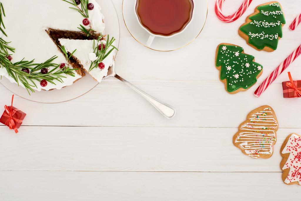 вид зверху на різдвяний пиріг, чашку чаю та ялинкове печиво на білому дерев'яному столі
 - Фото, зображення