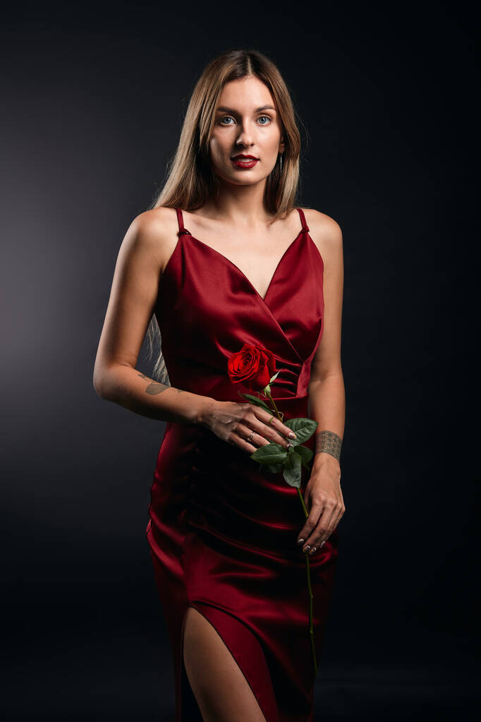 retrato de atractiva mujer de pelo justo impresionante en vestido rojo sosteniendo una rosa
 - Foto, Imagen
