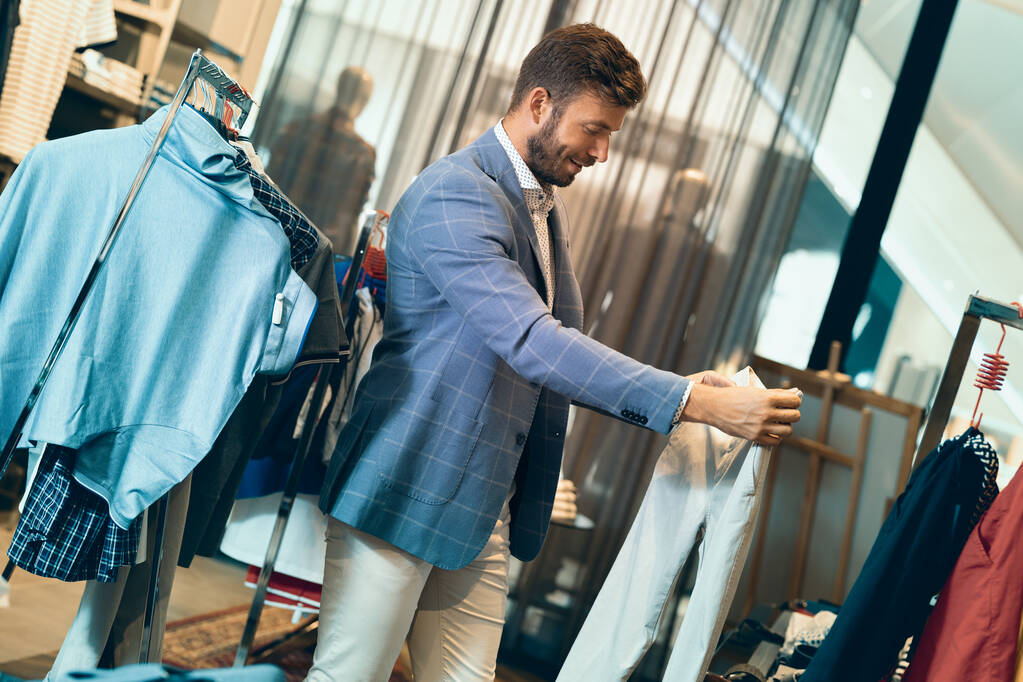 Uomo di tendenza nel negozio di abbigliamento maschile scegliendo pantaloncini
 - Foto, immagini