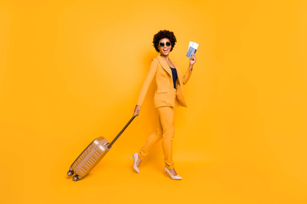 Pełna sylwetka profil boczny zdjęcie wesołej dziewczyny turystycznej trzymać pakiet dokumentów go kontroli paszportowej dotrzeć do miejsca weekendu nosić styl marynarka spodnie wysokie obcasy odizolowany żółty kolor tło - Zdjęcie, obraz