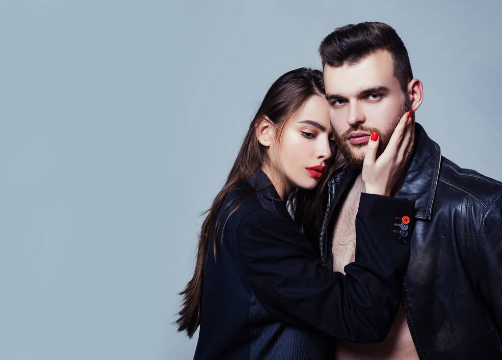 Passion fashion. Couple passionate people in love. Man brutal well groomed macho and attractive feminine girl long hair cuddling. Girlfriend passionate red lips and man leather jacket. Passionate hug - Photo, Image