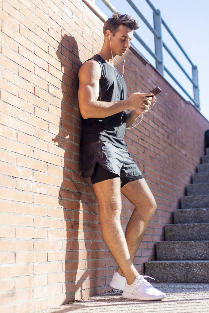 Портрет молодого человека, проверяющего спортивные результаты на смартфоне
 - Фото, изображение