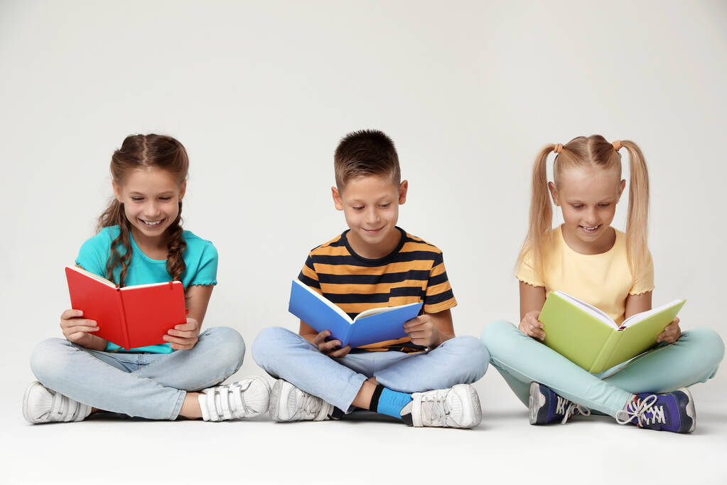 Μικρά παιδιά που διαβάζουν βιβλία σε γκρίζο φόντο - Φωτογραφία, εικόνα