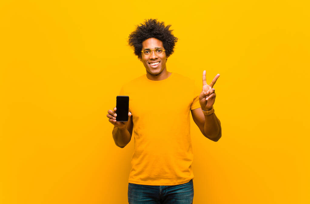 joven afroamericano hombre con un teléfono inteligente contra naranja bac
 - Foto, imagen