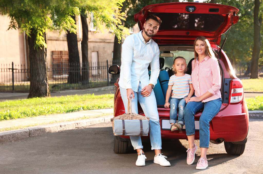 Famille heureuse avec panier de pique-nique assis dans le coffre de la voiture sur la route
 - Photo, image