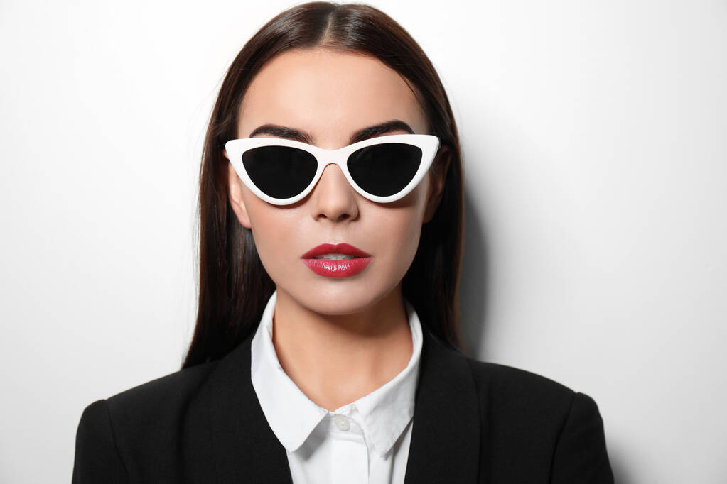 Молода бізнес-леді в стильних сонцезахисних окулярах на світлому фоні
 - Фото, зображення
