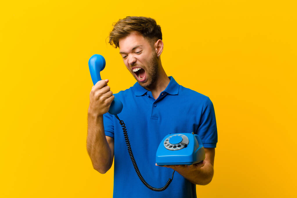 young man with a telephone against orange background - Photo, Image