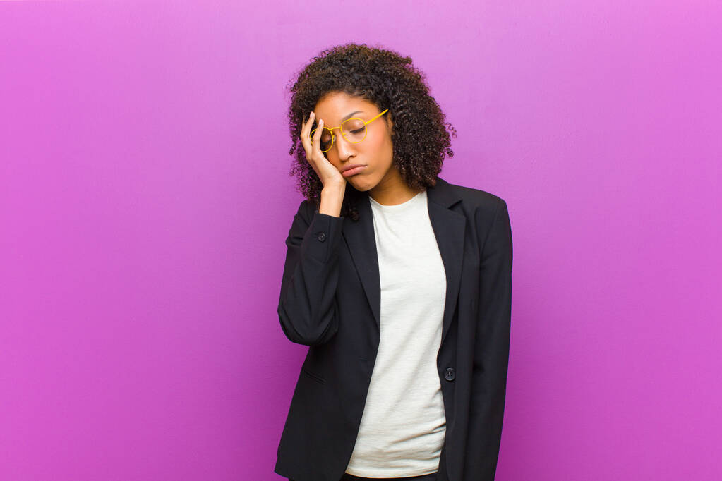 молодая чернокожая деловая женщина чувствует скуку, разочарование и сонливость после утомительной, скучной и утомительной задачи, держа лицо за руку
 - Фото, изображение