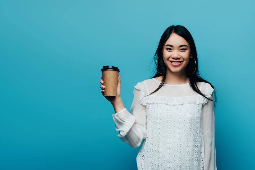 sorrindo morena asiática mulher segurando café para ir no fundo azul
 - Foto, Imagem