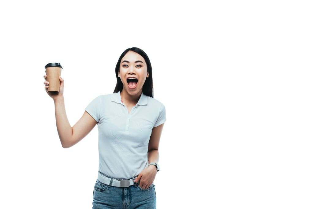 šťastný atraktivní asijské dívka s otevřenými ústy drží papírový šálek izolované na bílém - Fotografie, Obrázek