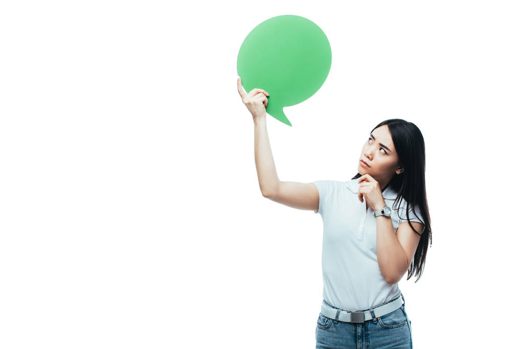 Düşünceli Asyalı kız, beyazda izole edilmiş yeşil boş konuşma balonuna bakıyor. - Fotoğraf, Görsel