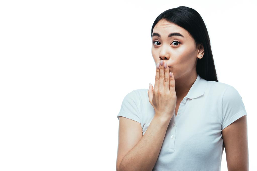 έκπληκτη ελκυστική ασιατική κοπέλα που καλύπτει το στόμα με το χέρι απομονώνονται σε λευκό - Φωτογραφία, εικόνα
