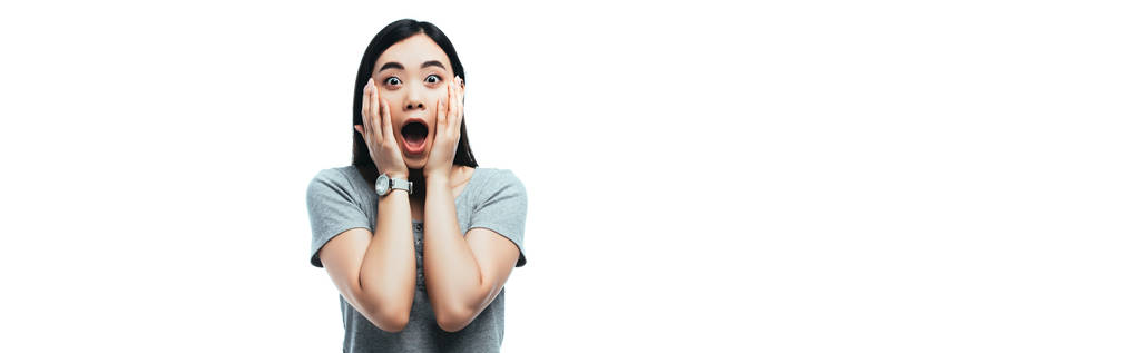 σοκαρισμένη Ασιάτισσα με ανοιχτό στόμα αγγίζοντας το πρόσωπο απομονώνονται σε λευκό, πανοραμική βολή - Φωτογραφία, εικόνα