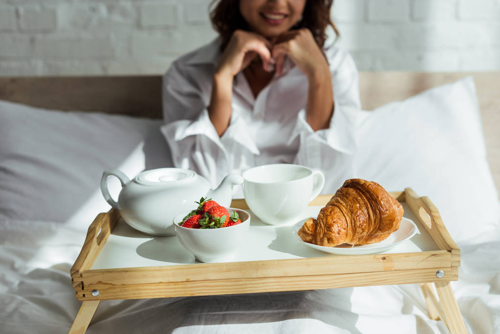 καλλιεργημένη θέα της γυναίκας με λευκό πουκάμισο που παίρνει πρωινό στο κρεβάτι το πρωί  - Φωτογραφία, εικόνα