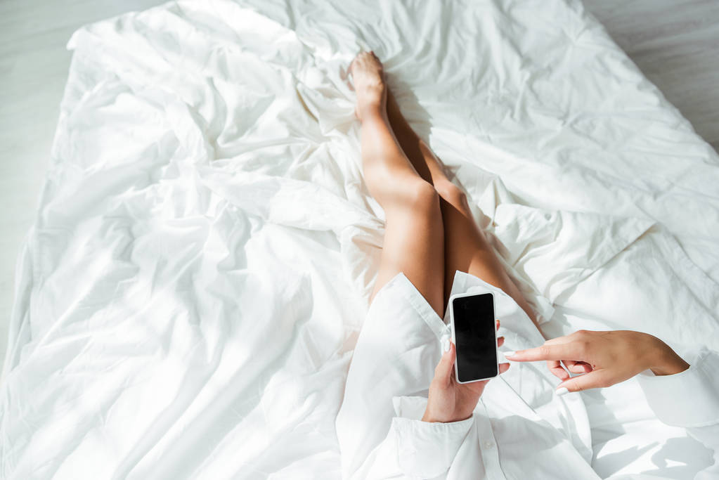 обрезанный вид женщины, указывающей пальцем на смартфон с копировальным пространством утром
  - Фото, изображение
