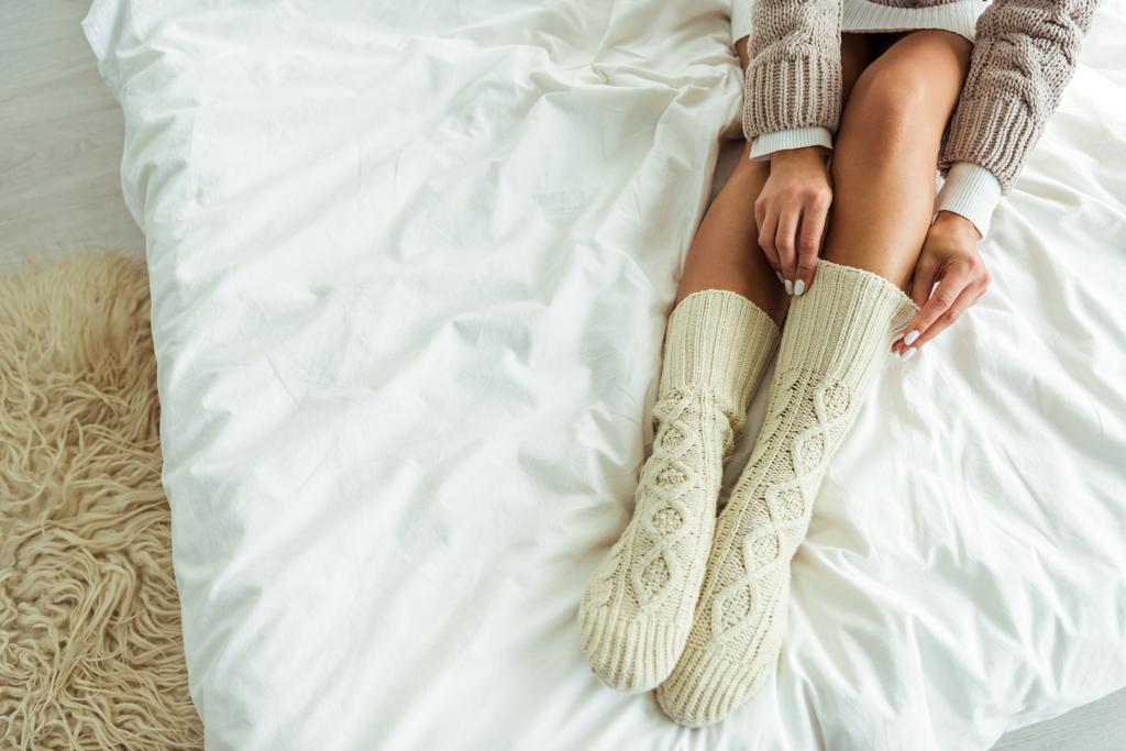 καλλιεργημένη άποψη της γυναίκας που παίρνει πλεκτές κάλτσες το πρωί  - Φωτογραφία, εικόνα