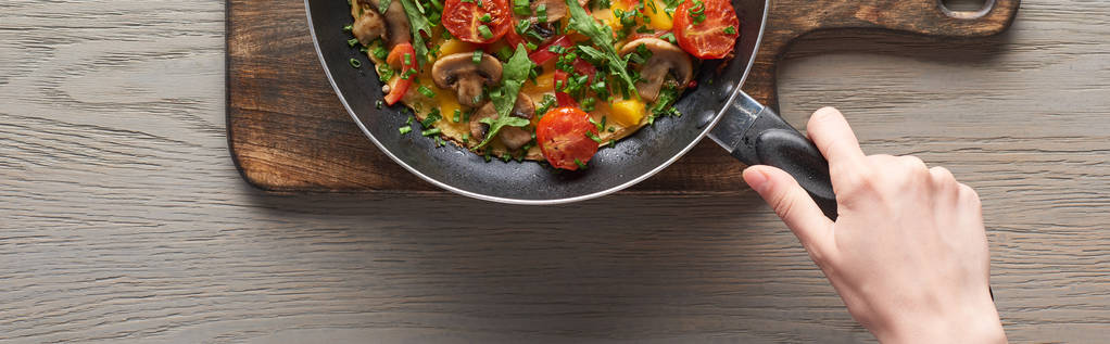 vista superior da omelete mulher cozinhar com cogumelos, tomates e verduras na frigideira
 - Foto, Imagem