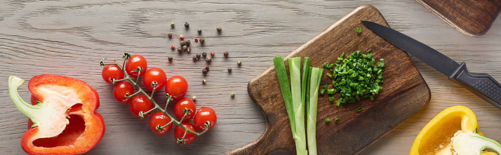 vista superior de pimentas frescas, tomates cereja e verduras em tábua de madeira com faca
  - Foto, Imagem
