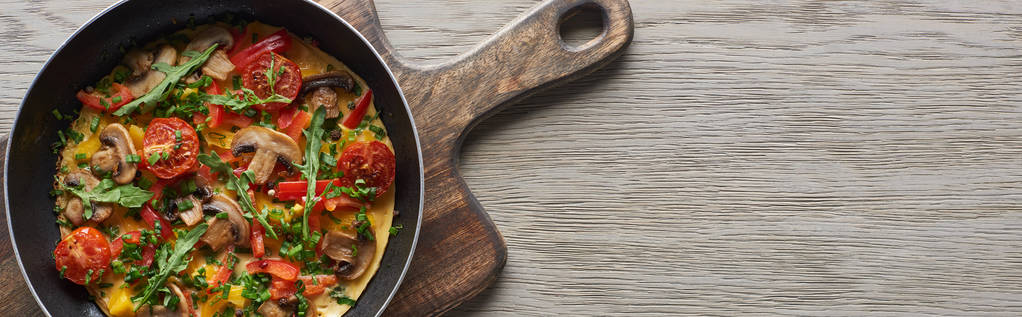 vista superior da omelete caseira para o café da manhã na frigideira na tábua de madeira
  - Foto, Imagem
