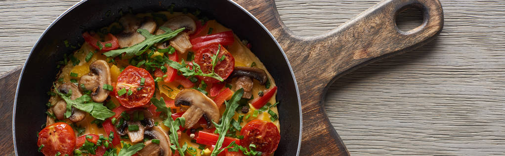 top view házi omlett zöldséggel és zöldséggel reggelire serpenyőben, fa táblán  - Fotó, kép