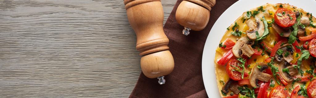 vista superior de omelete caseiro com legumes em mesa de madeira com pimenta e sal
 - Foto, Imagem