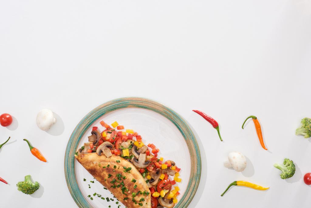 vista superior de la deliciosa tortilla envuelta con verduras en el plato con chiles frescos y brócoli
 - Foto, imagen
